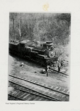 Train engine with three crew members standing in front of it.  