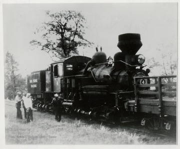Side view of Shay train engine.  Four men standing beside it.  Clyde Galford, Engineer.  