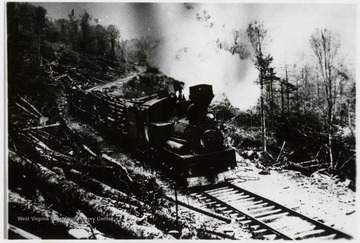 Shay engine with log cars traveling along hillside.