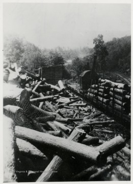 Lumber pile beside a log car.  