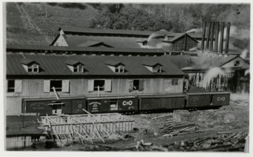 Front view of a mill and stacks.  C&amp;O train cars in front.  