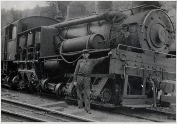 Train engine with a man standing beside it.  