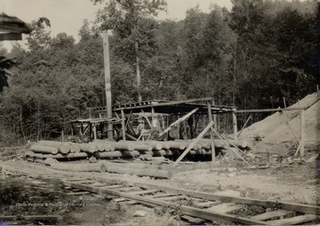 Man standing on top of logs.  'Sound logs of good quality are obtained from Appalachian hardwoods.  Selective logging and protection of young growth will insure continuous supplies of such logs.'