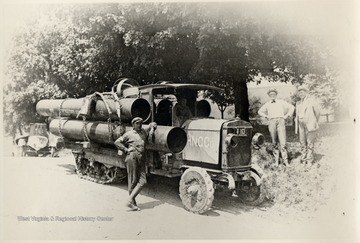Men standing beside a halftrack carrying oil equipment
