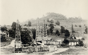 Four derricks with their adjoining oil company buildings.
