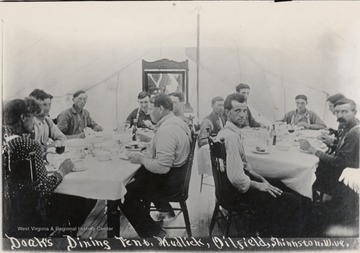 People sitting down at two tables eating a meal.  