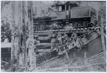 Men sitting on wreckage below trestle.