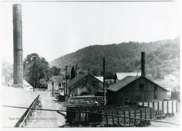 The old smoke stack in this picture (taken in 1931) was replaced in 1938 by a 125' stack.  Coal cars in foreground had been used many years previously for coal hauling from the salt work's own mine.  They were scrapped about 1935.  Note the two or three slender elm trees near the office.  These and several other beautiful elms, as well as nearly all other elms in this section, were killed by disease a few years later.