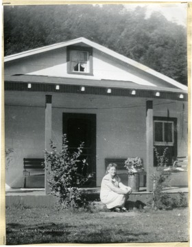 Mrs. J. B. Showalter home with a woman sitting on the porch after the outside improvement project in Slaty Fork, Pocohontas County. Improvements made:  built new windo casings, put asbestos shingles on house, built a front porch.  Cost Record: Asbestos Shingles-$80.48, Lumber and Nails-$80.48, Paint-$10.00, and Labor Costs-$50.00.  Together these all cost Mrs. Showalter 222.28.  (See photograph number 1576 for a view of the home before the improvements.)
