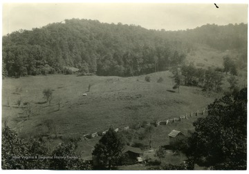 Farm house and fields and timber surrounding it.  Caption on back reads, 'Much of the farm woodland is adjacent to the farms and often forms large contiguous tracts of timber easily exploited.' U.S. Dept. of Agriculture, Bureau of Agricultural Economics, Photographic Section, No. 18443.