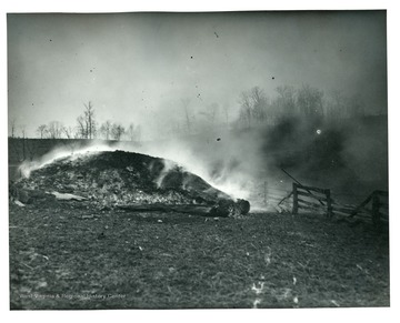 Smoke rising from a burning lime kiln on farm of W. A. Loar, Monongalia County, near Laurel Point, February 11, 1915.