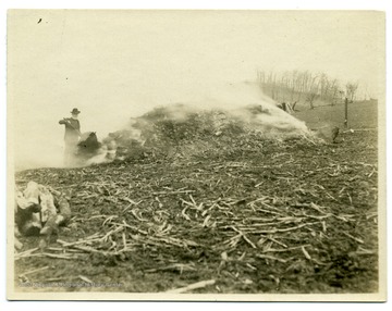 Man stands near a burning lime kiln on the farm of W. A. Loar in Monongalia County, near Laurel Point.