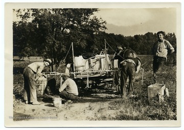 Men constructing a sprayer before starting work on the potato fields. Caption on back reads, 'Potatoes were raised cooperatively.'