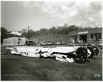 A continuous mining machine sits above ground in the yard of Lee-Norse Company Warehouses.