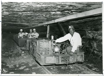 Julius Blaney driving a coal cart with people in a coal mine.
