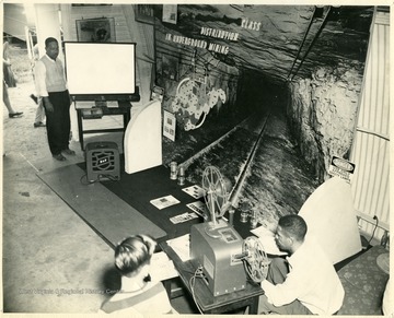 A display for coal safety with two men getting ready to start a film on a projector screen.