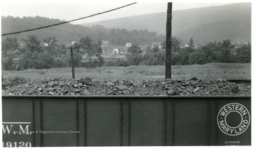 Filled Coal car with houses in background.