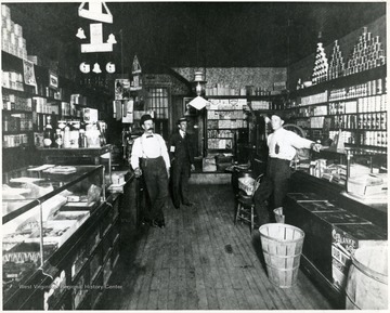 Three men standing in the company store at Montana Mines, W. Va. Store Manager Bartlett is first on left.