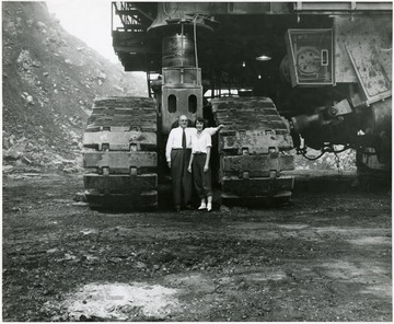 A man and woman standing next to a crawler track. 
