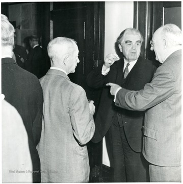 Two men talking with John Lewis.