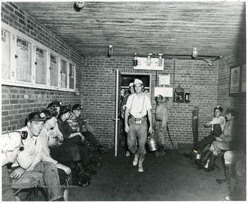 Miners entering a room with other miners sitting on benches lining the walls during a Consolidation Coal Co. Inspection trip.