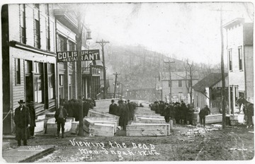 Men lined up to view caskets of the dead in the streets of Monongah. 