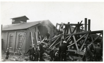 People stand near the wreckage after an explosion at a Thomas mine.