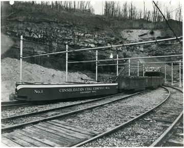 A miner operates a full coal cart out of the mine.