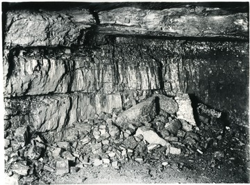 'Probably no phase of coal preparation requires the supervision and care that must be given to shooting practices. The type of explosive used is a safety powder known as "Duobel" and has been selected because it is most suitable for the coal mined in the White Oak Mines. Not only must the explosive be of the best quality and best suited for the work of breaking down the coal, but its use must be supervised and restricted. The proper amount to use; the size of the cartridge; the manner of tamping and many other details are looked after so that a maximum of lump and coarse coal is produced after shooting. This view shows the working place after the 'breaker shot' has been fired.'