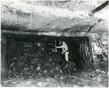 Miner works on pile of shot down coal.