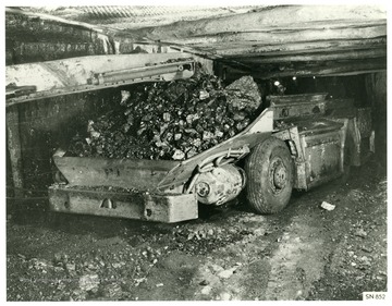 Miner operates a shuttle car that is loaded with coal.