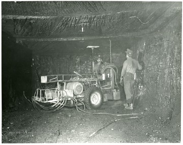 Two miners use equipment to secure the roof at the Pursglove No. 15 mine.