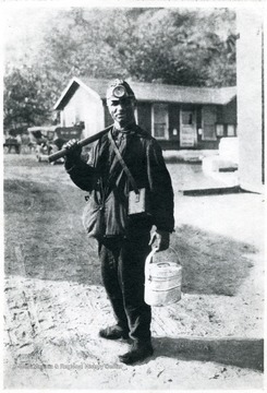 Miner poses with his lunch bucket and pick, ready for work.
