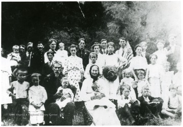 Group portrait of the Mooney family. 'This picture was taken in August, 1908. See ink mark on Big Woman. This is my mother. My father holding me next to Mom. The two old folks sitting at bottom are my Grandfather and Grandmother, Alfred Mooney and Liz, his wife, son of Ralph Mooney.' Note, negative cropped too close.
