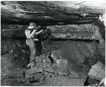 Miner in the process of placing charges into the coal seam at Bishop Mine.