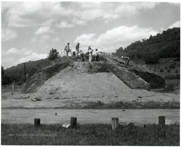 A group of men work on excavating and old Adena Indian mound.