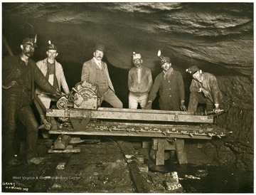 Six miners pose by a electrical cutting machine in a mine in Preston County.
