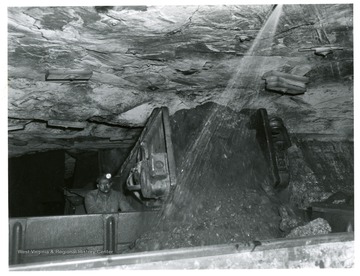 Miner unloading coal into car while it is being sprayed to retard dust.