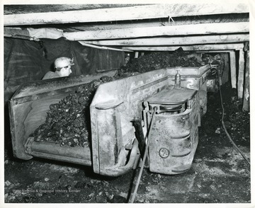 A miner operating an electric shuttle car filled with coal.