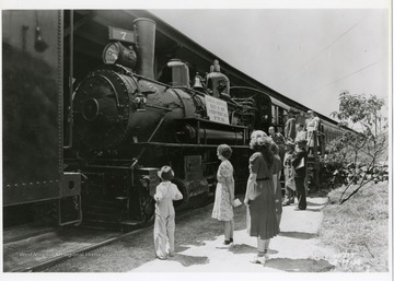 Group of people examine a class G.I. Locomotive.  Sign reads: Built in 1897 a heavy freight locomotive of the 90's.