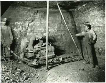 Three miners work on a piece of machinery at Elkhorn, W. Va.