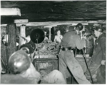 'Scene from a coal mine 300 ft. under a mountain in W. Va., where W.E. Austin, movie cameraman for the Norfolk and Western RR is shown taking what are believed to be first color movies inside a mine.'