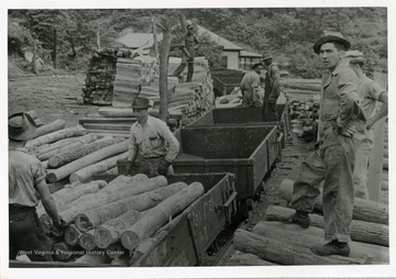 Men loading logs in coal carts.