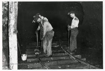 Three miners work on the rail track in the mine.