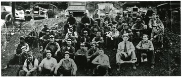 Group portrait of miners sitting on a hillside.