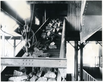 'All sizes of 'White' prepared coal is loaded into railroad cars with loading booms to minimize breakage and preserve the best appearance of the coal. It would be useless to carefully mine and screen our coal if we did not use proper care in loading it into the railroad cars. These booms lower to the bottom of the car when it is first placed under the tipple for loading, and raised from time to time as the car fills up. Note how perfectly screened this lump coal appears on the boom! Not a sign of slack to be seen. Treated for dust if desired.'