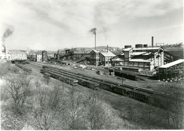 Line of large coal buildings. Filled coal cars lined up outside as well.