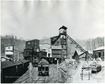 Railroad Cars filled with coal lined up outside plant buildings.
