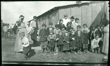 Portrait of children and some women and men gathered outside a barracks.