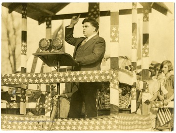 John L. Lewis standing on a platform decorated in stars and stripes.